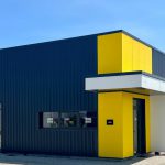 Façade du bâtiment de Tims à Valence, avec un design moderne en noir et des angles jaunes distinctifs. Le contraste entre les couleurs donne au bâtiment un aspect contemporain et attractif.